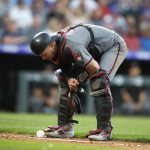 Arizona Diamondbacks catcher Carson Kelly watches to see if a ground ball off the bat of Colorado Rockies' Raimel Tapia remains in fair territory for a single in the third inning of a baseball game Monday, Aug. 12, 2019, in Denver. Tapia was awarded the single. (AP Photo/David Zalubowski)