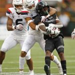 Arizona safety Scottie Young Jr. (6) watches as linebacker Colin Schooler (7) pulls down Hawaii wide receiver Cedric Byrd II (6) during the first half of an NCAA college football game Saturday, Aug. 24, 2019, in Honolulu. (AP Photo/Marco Garcia)