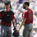 From left, umpire Chris Conroy confers with Arizona Diamondbacks catcher Carson Kelly and starting pitcher Robbie Ray as he waits to be pulled from the mound before the start of the bottom of the third inning of a baseball game against the Colorado Rockies Wednesday, Aug. 14, 2019, in Denver. Relief pitcher Matt Andriese took over on the mound for Ray. (AP Photo/David Zalubowski)