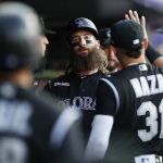Colorado Rockies' Charlie Blackmon, center, is congratulated by teammates as he returns to the dugout after scoring on a single by Raimel Tapia off Arizona Diamondbacks starting pitcher Merrill Kelly in the first inning of a baseball game Monday, Aug. 12, 2019, in Denver. (AP Photo/David Zalubowski)