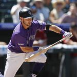 Colorado Rockies' Garrett Hampson puts down a bunt single to drive in a runner from third base against Arizona Diamondbacks starting pitcher Robbie Ray in the second inning of a baseball game Wednesday, Aug. 14, 2019, in Denver. (AP Photo/David Zalubowski)