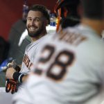 San Francisco Giants' Evan Longoria smiles in the dugout while looking at Buster Posey after hitting a two-run home run off Arizona Diamondbacks' Alex Young during the fifth inning of a baseball game Thursday, Aug. 15, 2019, in Phoenix. (AP Photo/Darryl Webb)