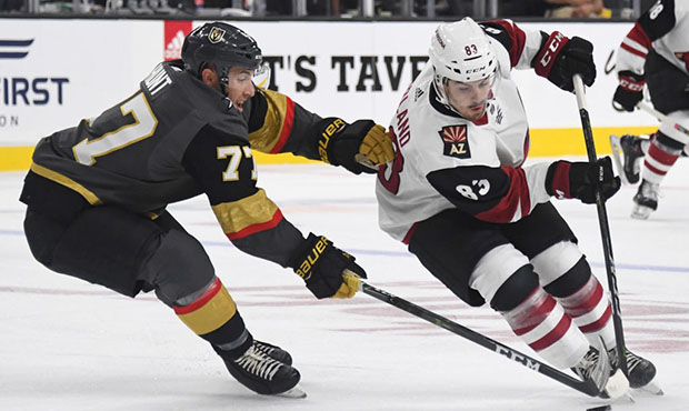 Conor Garland #83 of the Arizona Coyotes skates with the puck against Brad Hunt #77 of the Vegas Go...