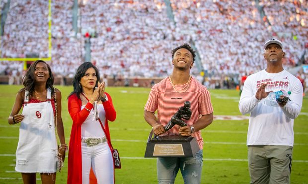 Kyler Murray (second from right) holds up the Heisman Trophy, joined by (from left) his cousin, Car...