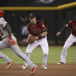 Arizona Diamondbacks third baseman Jake Lamb, middle, fields a grounder between St. Louis Cardinals' Randy Arozarena, left, and Diamondbacks' shortstop Nick Ahmed (13) before throwing to first base for the out during the eighth inning of a baseball game Wednesday, Sept. 25, 2019, in Phoenix. The Diamondbacks defeated the Cardinals 9-7. (AP Photo/Ross D. Franklin)