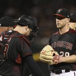 Arizona Diamondbacks starting pitcher Merrill Kelly, right, gets a visit to the mound from Diamondbacks catcher Carson Kelly, middle, and Diamondbacks pitching coach Mike Butcher, left, during the fifth inning of a baseball game against the Cincinnati Reds, Saturday, Sept. 14, 2019, in Phoenix. The Diamondbacks defeated the Reds 1-0. (AP Photo/Ross D. Franklin)