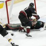 Arizona Coyotes' Jordan Oesterle (82) tries to protect Arizona Coyotes goalie Darchy Kuemper (35) as Kuemper goes spread eagle, trying  to save a shot against the Boston Bruins' Charlie Coyle (13) during the third period of an NHL hockey game Saturday, Oct. 5, 2019, in Glendale, Ariz. (AP Photo/Darryl Webb)