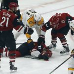 Arizona Coyotes defenseman Jordan Oesterle (82) lies on the ice after getting hit with the puck as Derek Stepan (21), Phil Kessel (81) and Nashville Predators left wing Austin Watson (51) try to help him in the first period during an NHL hockey game, Thursday, Oct. 17, 2019, in Glendale, Ariz. (AP Photo/Rick Scuteri)