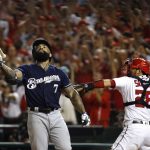 Milwaukee Brewers' Eric Thames, left, flips his bat after striking out in front of Washington Nationals catcher Kurt Suzuki in the ninth inning of a National League wild-card baseball game, Tuesday, Oct. 1, 2019, in Washington. Washington won 4-3. (AP Photo/Patrick Semansky)