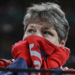 Cathy Butcher tries to keep warm during the second inning of Game 1 of the baseball National League Championship Series between the St. Louis Cardinals and the Washington Nationals Friday, Oct. 11, 2019, in St. Louis. (AP Photo/Jeff Roberson)