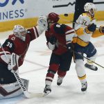 Arizona Coyotes defenseman Jordan Oesterle (82) is hit in the back of the head with a puck in front of goaltender Darcy Kuemper (35) as Nashville Predators left wing Austin Watson (51) tries to avoid the hit in the first period during an NHL hockey game, Thursday, Oct. 17, 2019, in Glendale, Ariz. (AP Photo/Rick Scuteri)