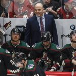 Arizona Coyotes head coach Rick Tocchet shares a laugh with Jason Demers (55) during the third period of an NHL hockey game Saturday, Oct. 5, 2019, in Glendale, Ariz. (AP Photo/Darryl Webb)