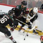 Boston Bruins' Chris Wagner (14) gets pinned up against the boards by the Arizona Coyotes' Niklas Hjalmarsson (4) and Christian Fischer (36) during the second period of an NHL hockey game Saturday, Oct. 5, 2019, in Glendale, Ariz. (AP Photo/Darryl Webb)