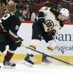 Boston Bruins' Jake BeBrusk (74) gets a shot off against the Arizona Coyotes' Jordan Oesterle (82) during the first period of an NHL hockey game Saturday, Oct. 5, 2019, in Glendale, Ariz. (AP Photo/Darryl Webb)