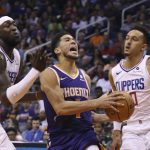 Phoenix Suns guard Devin Booker, center, is fouled as he drives past LA Clippers forward Montrezl Harrell, left, and Clippers guard Landry Shamet, right, during the second half of a basketball game Saturday, Oct. 26, 2019, in Phoenix. The Suns defeated the Clippers 130-122. (AP Photo/Ross D. Franklin)