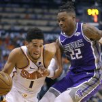 Phoenix Suns guard Devin Booker (1) drives on Sacramento Kings forward Richaun Holmes during the second half of an NBA basketball game Wednesday, Oct. 23, 2019, in Phoenix. (AP Photo/Rick Scuteri)