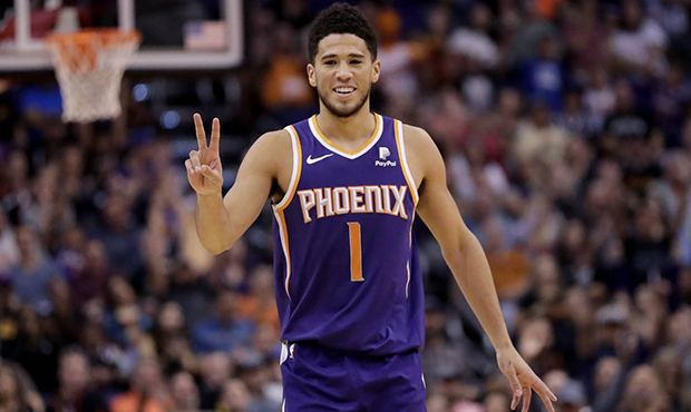 Phoenix Suns guard Devin Booker motions to a teammate after a basket during the first half of the t...