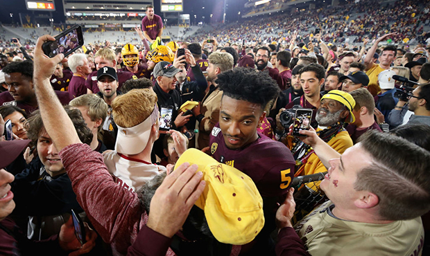 Quarterback Jayden Daniels #5 of the Arizona State Sun Devils is surrounded by fans on the field af...