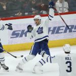 Toronto Maple Leafs left wing Pierre Engvall, center, has trouble celebrating his goal against the Arizona Coyotes as he loses his balance between Maple Leafs defensemen Morgan Rielly (44) and Justin Holl (3) during the second period of an NHL hockey game Thursday, Nov. 21, 2019, in Glendale, Ariz. (AP Photo/Ross D. Franklin)