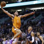 Phoenix Suns guard Devin Booker dunks over Dallas Mavericks forward Kristaps Porzingis (6) during the second half of an NBA basketball game Friday, Nov. 29, 2019, in Phoenix. The Mavericks won 120-113. (AP Photo/Rick Scuteri)