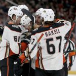 Anaheim Ducks Tory Terry (61) and Rickard Rakell (67) and others surround rookie Brendan Guhle (2) after he scored his first NHL goal against the Arizona Coyotes during the first period of an NHL hockey game Wednesday, Nov. 27, 2019, in Glendale, Ariz. (AP Photo/Darryl Webb)