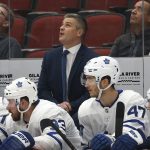 New Toronto Maple Leafs head coach Sheldon Keefe, top center, looks at the scoreboard during the first period of an NHL hockey game against the Arizona Coyotes, Thursday, Nov. 21, 2019, in Glendale, Ariz. (AP Photo/Ross D. Franklin)