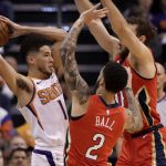 Phoenix Suns guard Devin Booker, left, is pressured by New Orleans Pelicans guard Lonzo Ball (2) and forward Nicolo Melli during the first half of an NBA basketball game, Thursday, Nov. 21, 2019, in Phoenix. (AP Photo/Matt York)