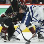 Arizona Coyotes left wing Christian Dvorak (18) and Toronto Maple Leafs center Zach Hyman (11) work for the puck during the third period of an NHL hockey game Thursday, Nov. 21, 2019, in Glendale, Ariz. The Maple Leafs won 3-1. (AP Photo/Ross D. Franklin)