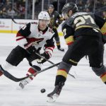 Arizona Coyotes center Clayton Keller (9) knocks the puck up the ice against Vegas Golden Knights defenseman Shea Theodore (27) during the third period of an NHL hockey game Friday, Nov. 29, 2019, in Las Vegas. (AP Photo/John Locher)