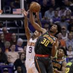 Atlanta Hawks center Damian Jones (30) rebounds over Phoenix Suns forward Kelly Oubre Jr. (3) during the first half of an NBA basketball game Thursday, Nov. 14, 2019, in Phoenix. (AP Photo/Matt York)