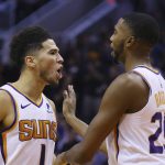 Phoenix Suns guard Devin Booker (1) shouts at Philadelphia 76ers players after scoring and being fouled as teammate Mikal Bridges (25) holds him back during the second half of an NBA basketball game, Monday, Nov. 4, 2019, in Phoenix. The Suns defeated the 76ers 114-109. (AP Photo/Ross D. Franklin)