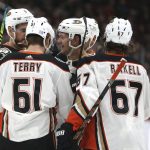 Anaheim Ducks Tory Terry (61) and Rickard Rakell (67) and others surround rookie Brendan Guhle (center) after he scored his first NHL goal against the Arizona Coyotes during the first period of an NHL hockey game Wednesday, Nov. 27, 2019, in Glendale, Ariz. (AP Photo/Darryl Webb)