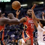 New Orleans Pelicans guard E'Twaun Moore (55) dishes off to guard Jrue Holiday (11) as Phoenix Suns forward Cameron Johnson (23) defends during the first half of an NBA basketball game, Thursday, Nov. 21, 2019, in Phoenix. (AP Photo/Matt York)