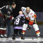 Arizona Coyotes' Oliver Ekman-Larsson (23) drops the puck in front of Leighton Accardo, middle, who is battling cancer, and Calgary Flames' Mark Giordano (5) during an NHL Fights Cancer puck drop ceremony prior to an NHL hockey game, Saturday, Nov. 16, 2019, in Glendale, Ariz. (AP Photo/Ross D. Franklin)