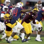 Arizona's Khalil Tate (14) just gets rid of the ball as Arizona State's Evan Fields (4) tries to bring him down during the first half of an NCAA college football game, Saturday, Nov. 30, 2019, in Tempe, Ariz. (AP Photo/Darryl Webb)