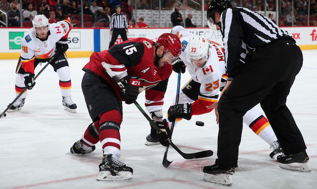 Brad Richardson #15 of the Arizona Coyotes faces off against Sean Monahan #23 of the Calgary Flames...