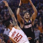 Phoenix Suns guard Devin Booker (1) shoots over Houston Rockets guard Austin Rivers (25) during the second half of an NBA basketball game Saturday, Dec. 21, 2019, in Phoenix. (AP Photo/Ross D. Franklin)
