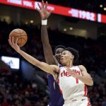 Portland Trail Blazers guard Anfernee Simons, right, shoots over Phoenix Suns center Deandre Ayton during the second half of an NBA basketball game in Portland, Ore., Monday, Dec. 30, 2019. (AP Photo/Craig Mitchelldyer)