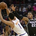 Phoenix Suns guard Devin Booker, center, is defended by the Sacramento Kings guard Buddy Hield, left, and Kings forward Richaun Holmes, right, during the first quarter of an NBA basketball game in Sacramento, Calif., Saturday, Dec. 28, 2019. (AP Photo/Hector Amezcua)