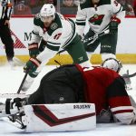 Arizona Coyotes goaltender Darcy Kuemper, front, stops the puck just enough to make a save on a shot by Minnesota Wild left wing Marcus Foligno (17) during the third period of an NHL hockey game Thursday, Dec. 19, 2019, in Glendale, Ariz. The Wild won 8-5. (AP Photo/Ross D. Franklin)