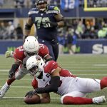 Arizona Cardinals middle linebacker Jordan Hicks, lower right, recovers a fumble by Seattle Seahawks wide receiver David Moore (not shown) as Cardinals' Jalen Thompson (34) looks on during the second half of an NFL football game, Sunday, Dec. 22, 2019, in Seattle. (AP Photo/Lindsey Wasson)