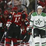 Dallas Stars right wing Corey Perry (10) skates past as Arizona Coyotes left wing Taylor Hall (91) celebrates his goal with defenseman Aaron Ness (42), defenseman Ilya Lyubushkin (46) and right wing Conor Garland (83) during the first period of an NHL hockey game Sunday, Dec. 29, 2019, in Glendale, Ariz. (AP Photo/Ross D. Franklin)