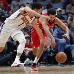 Phoenix Suns guard Devin Booker (1) and New Orleans Pelicans guard Kenrich Williams reach for the ball during the first half of an NBA basketball game in New Orleans, Thursday, Dec. 5, 2019. (AP Photo/Gerald Herbert)