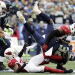 Seattle Seahawks running back Chris Carson (32) is tackled by Arizona Cardinals linebacker Chandler Jones (55) above Cardinals strong safety Budda Baker, lower left, during the first half of an NFL football game, Sunday, Dec. 22, 2019, in Seattle. (AP Photo/Lindsey Wasson)