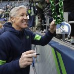Seattle Seahawks head coach Pete Carroll gives autographs to fans before an NFL football game against the Arizona Cardinals, Sunday, Dec. 22, 2019, in Seattle. (AP Photo/Elaine Thompson)