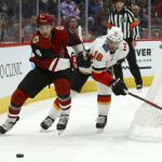 Arizona Coyotes center Nick Schmaltz (8) and Calgary Flames center Tobias Rieder (16) battle for the puck during the second period of an NHL hockey game Tuesday, Dec. 10, 2019, in Glendale, Ariz. (AP Photo/Ross D. Franklin)