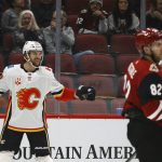 Calgary Flames right wing Michael Frolik, left, celebrates his goal with Flames center Zac Rinaldo (36) as Arizona Coyotes defenseman Jordan Oesterle (82) skates past during the first period of an NHL hockey game, Tuesday, Dec. 10, 2019 in Glendale, Ariz. (AP Photo/Ross D. Franklin)