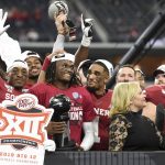 Oklahoma wide receiver CeeDee Lamb, center, holds the Most Outstanding Player award as he is congratulated by quarterback Jalen Hurts (1) after their 30-23 overtime victory over Baylor in an NCAA college football game for the Big 12 Conference championship, Saturday, Dec. 7, 2019, in Arlington, Texas. (AP Photo/Jeffrey McWhorter)