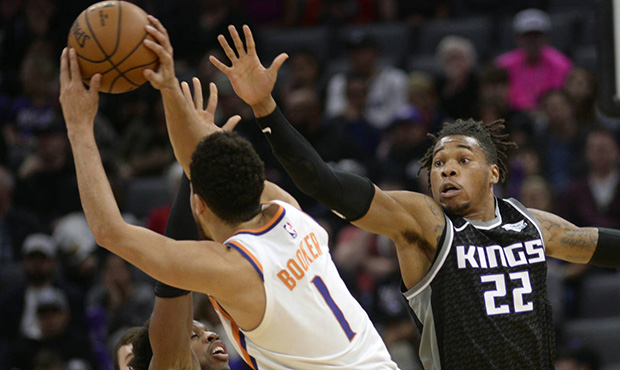 Phoenix Suns guard Devin Booker, center, is defended by the Sacramento Kings guard Buddy Hield, lef...
