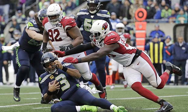 Seattle Seahawks quarterback Russell Wilson (3) slides to avoid a tackle by Arizona Cardinals lineb...